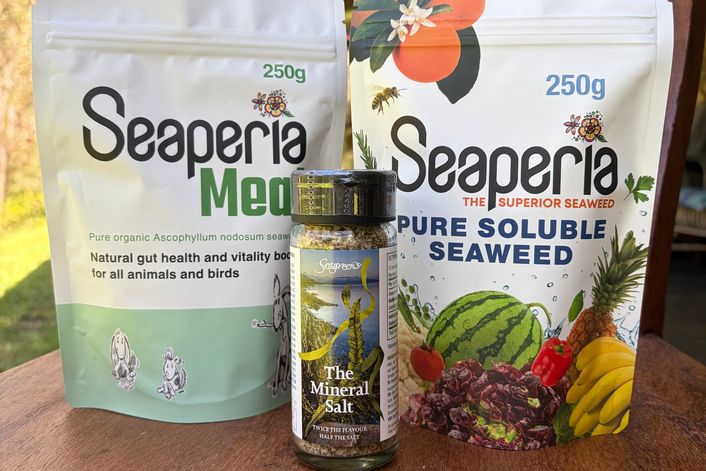 Two packages of Seaperia seaweed on a wooden surface with a blurred outdoor background.