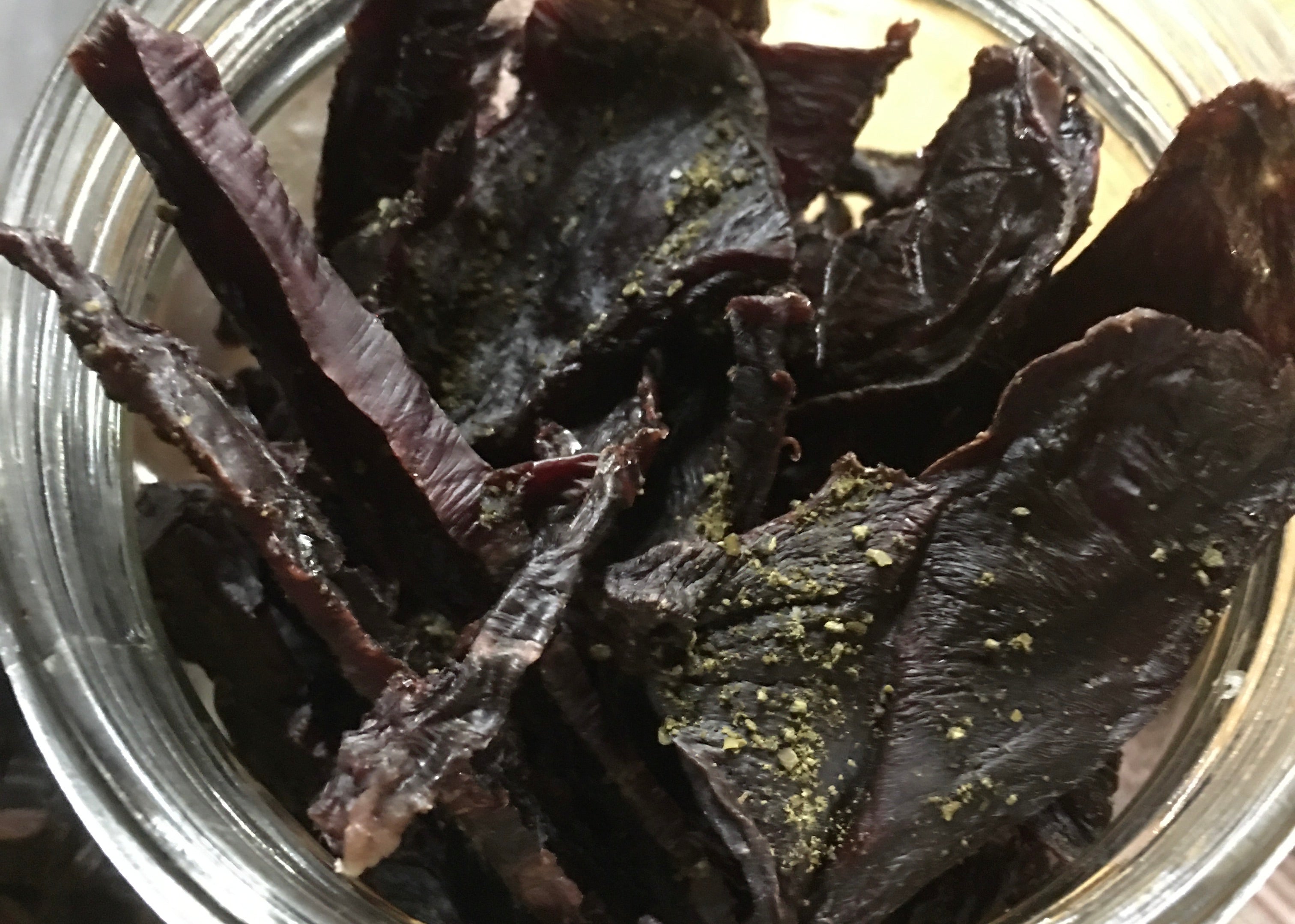 A close up of seaweed sprinkles on dehydrtated beef heart dog treats.