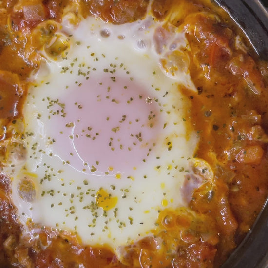 An egg in tomato sauce bubbling in a cast iron pot sprinkled with Seagreens Ruby One