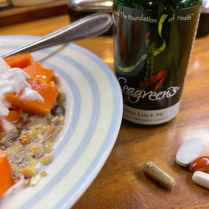 Seagreens supplement bottle with a plate of fruit and muesli with pills on a wooden surface