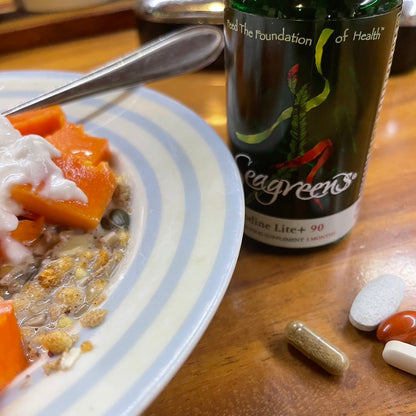 Seagreens supplement bottle with a plate of fruit and muesli with pills on a wooden surface