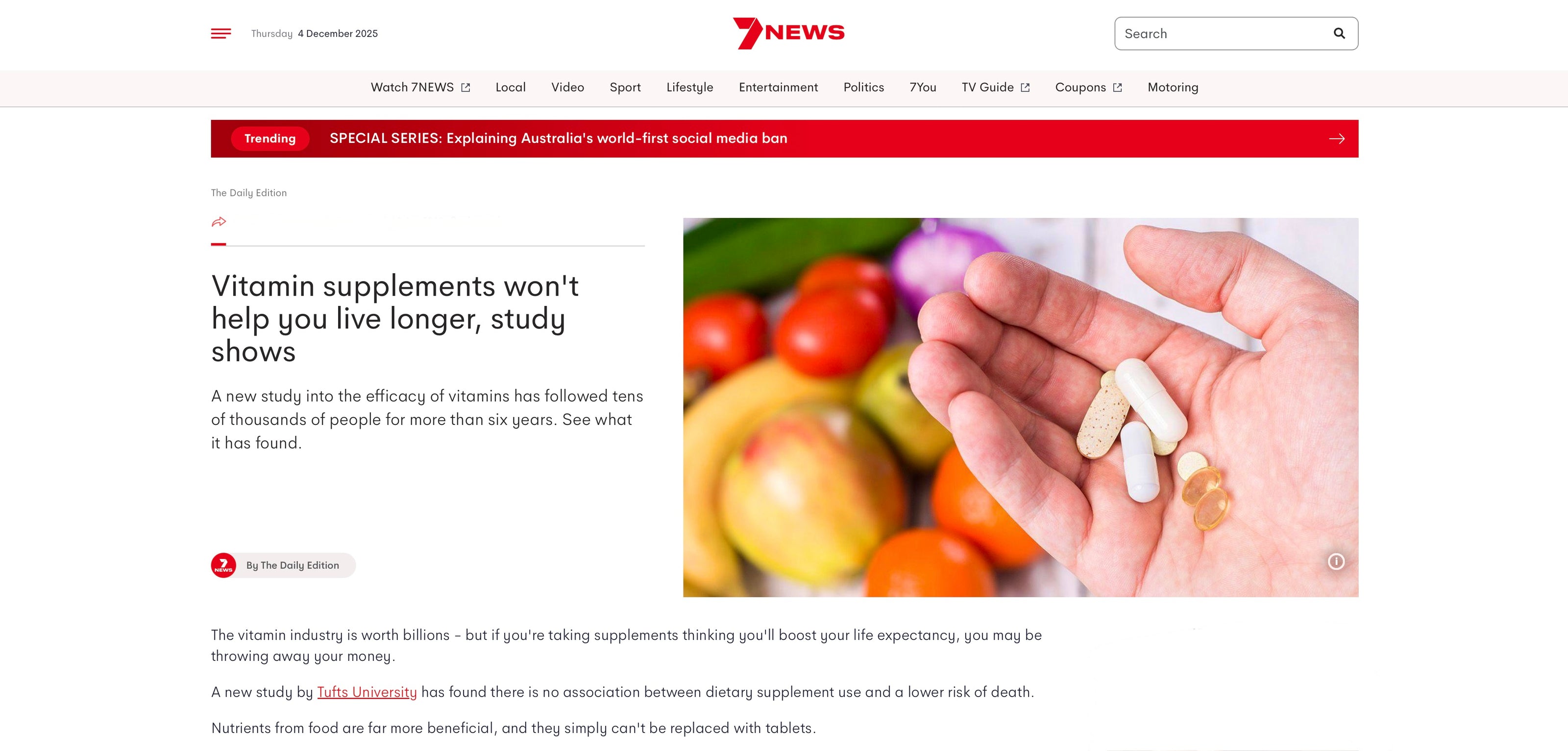 News article about vitamin supplements on a website with a hand holding pills and fruits.